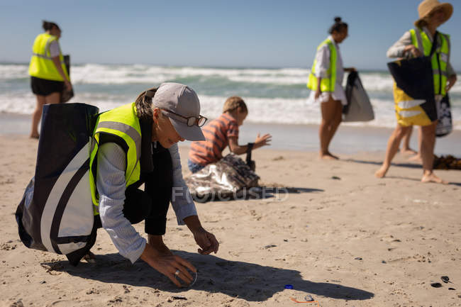 Вид на многонациональных волонтеров, очищающих пляж в солнечный день — стоковое фото