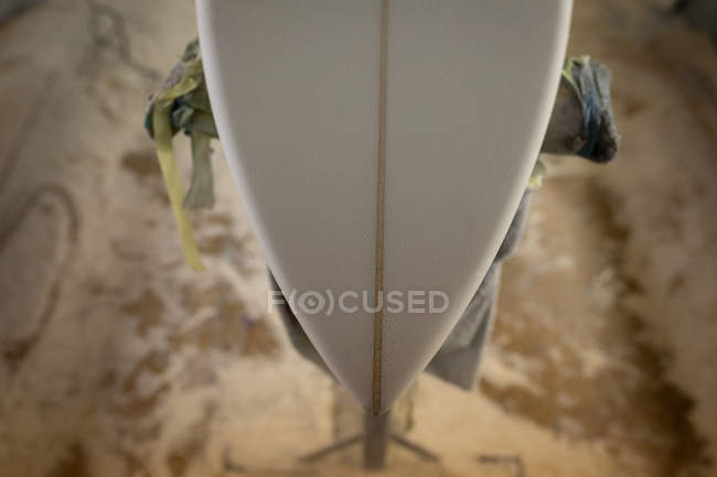 Gros plan de l'extrémité d'une planche de surf sur un stand de réparation en atelier — Photo de stock