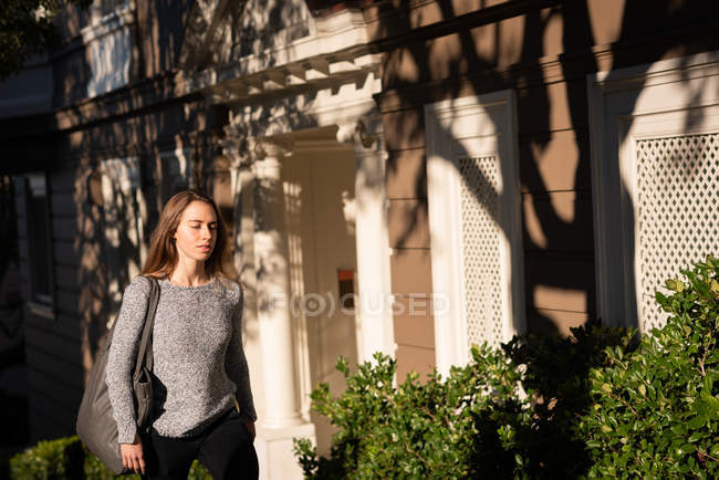 Vista frontal de la mujer caminando por la calle en un día soleado - foto de stock