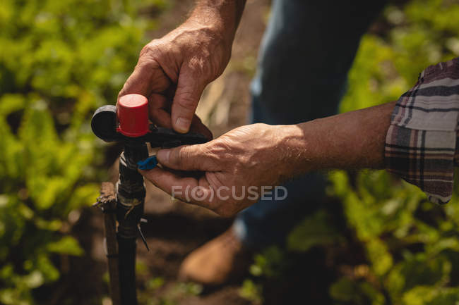 Close-up view of male farmer repairing valve pipe in farm on a sunny day — Stock Photo