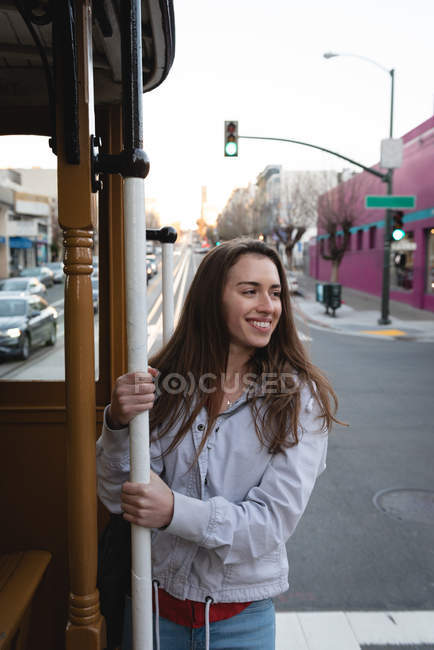 Vista frontal de la joven mujer caucásica feliz colgando fuera del vehículo en movimiento en la ciudad - foto de stock