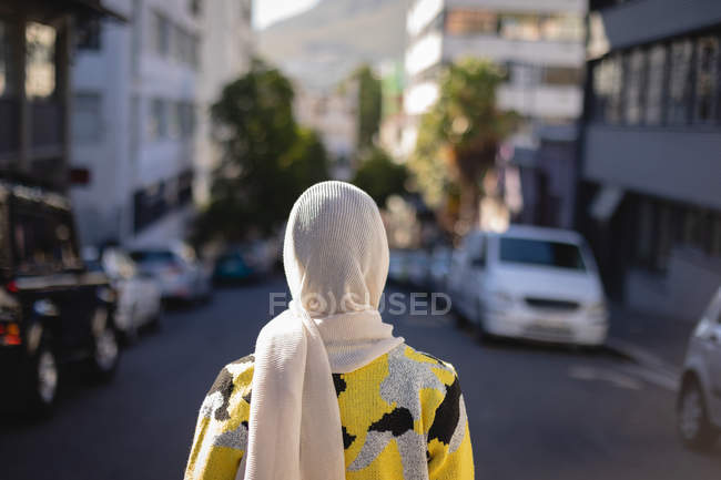 Вид сзади на молодую женщину, стоящую на улице в солнечный день — стоковое фото