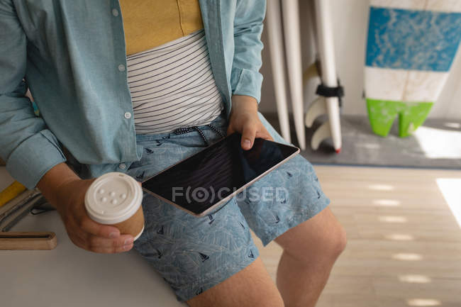 Sezione media dell'uomo che usa il computer portatile mentre prende un caffè in un laboratorio — Foto stock