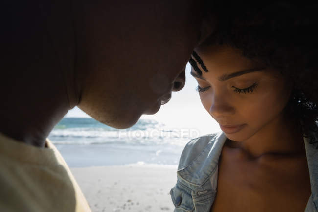 Vue latérale d'heureux couple afro-américain romantique debout à la plage par une journée ensoleillée — Photo de stock