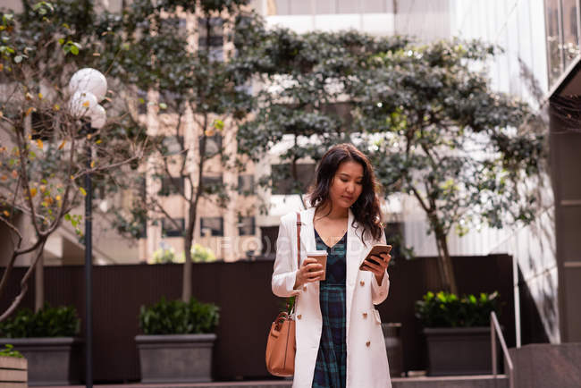 Vorderansicht einer asiatischen Frau, die auf der Straße steht und ihr Handy benutzt — Stockfoto