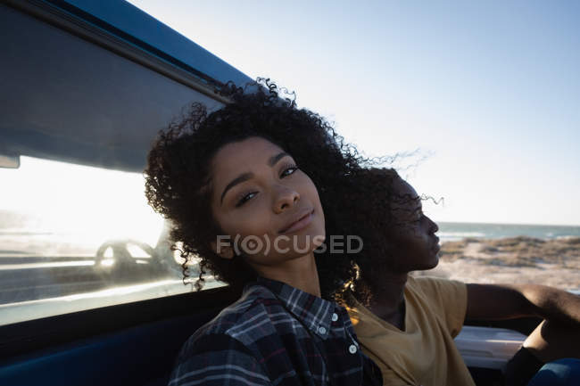 Vue latérale du couple afro-américain se détendre en voiture à la plage par une journée ensoleillée — Photo de stock