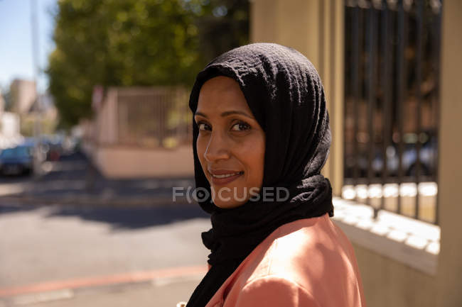 Side view of beautiful Mixed race woman standing and looking at camera in the street on a sunny day — Stock Photo