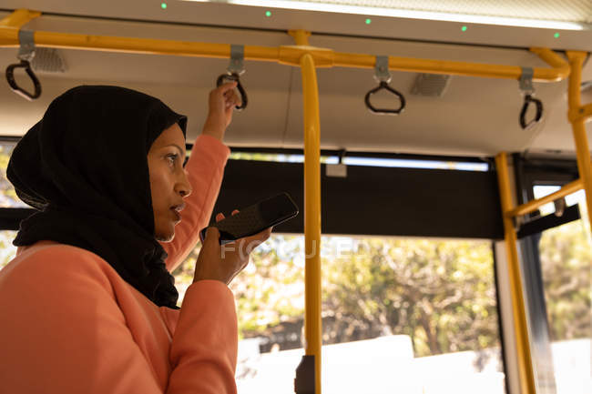 Seitenansicht einer schönen Mischlingshündin, die im Bus auf ihrem Handy spricht — Stockfoto
