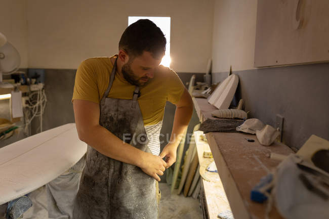 Frontansicht eines kaukasischen Mannes mit Schürze in einer Werkstatt — Stockfoto