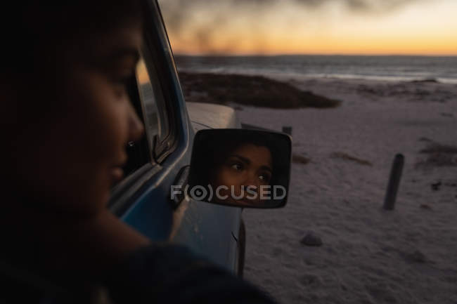 Вид збоку красива жінка думає, сидячи в машині на пляжі — стокове фото