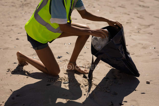 Low section of female volunteer cleaning beach on a sunny day — Stock Photo