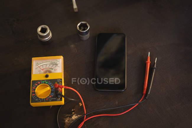 Motor testing multimeter and mobile phone at floor in garage — Stock Photo