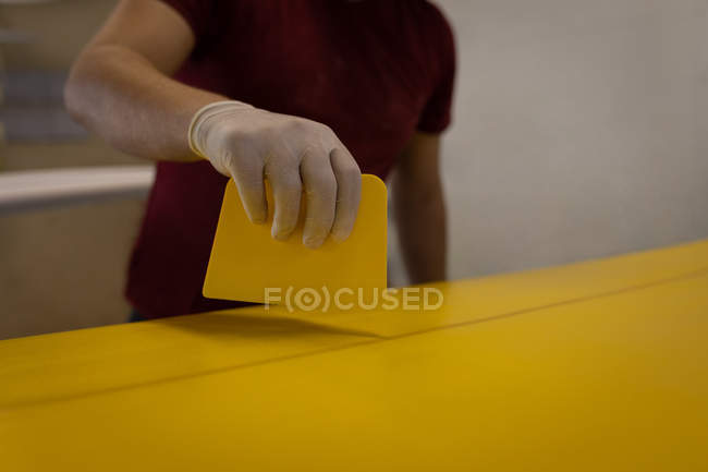 Partie médiane de la planche de surf peinture homme jaune dans l'atelier — Photo de stock