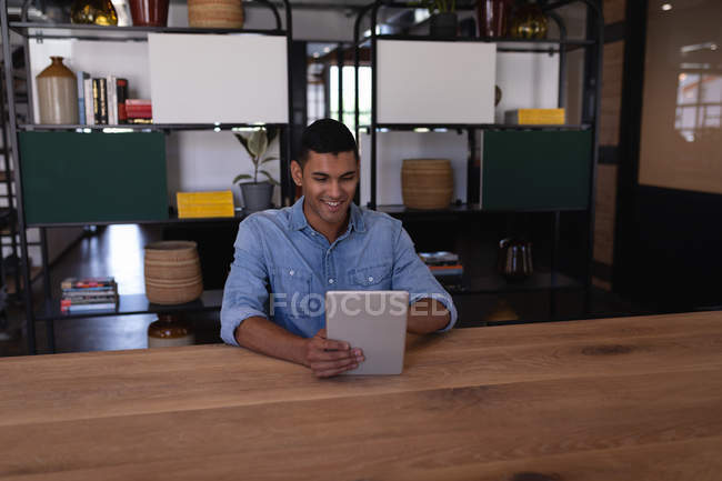 Frontansicht eines glücklichen gemischten Geschäftsmannes mit digitalem Tablet am Schreibtisch im modernen Büro — Stockfoto