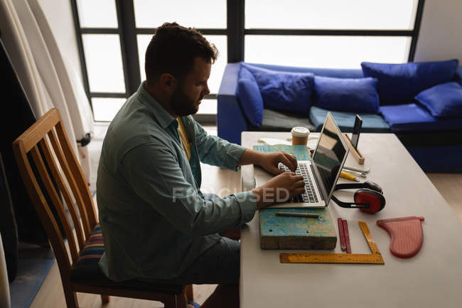 Seitenansicht eines kaukasischen Mannes mit Laptop in einer Werkstatt — Stockfoto