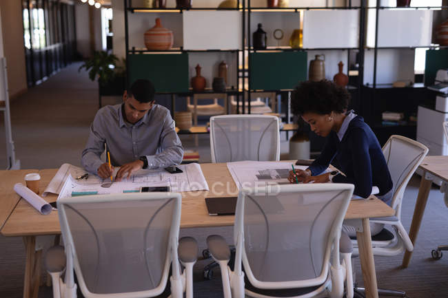 Vista ad alto angolo di giovani focalizzati Uomini d'affari di razza mista che lavorano su piani in una sala riunioni in un ufficio moderno — Foto stock