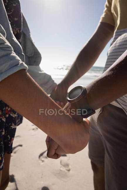 Vista lateral do casal segurando ambas as mãos na praia no dia ensolarado — Fotografia de Stock