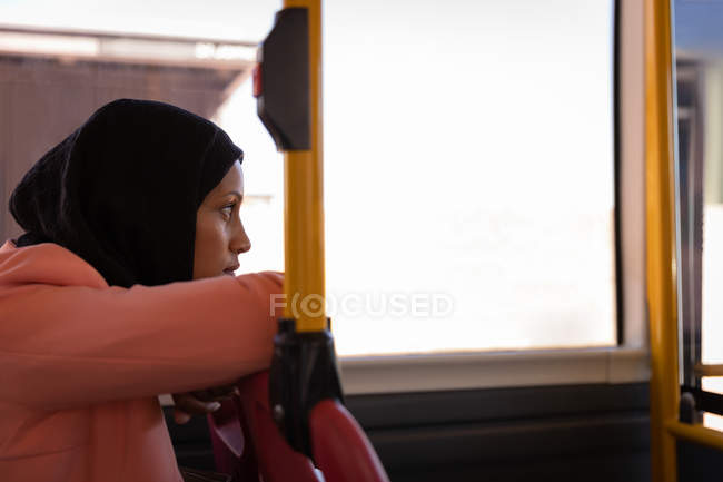 Side view of a thoughtful mixed-race woman sitting while traveling in bus — Stock Photo