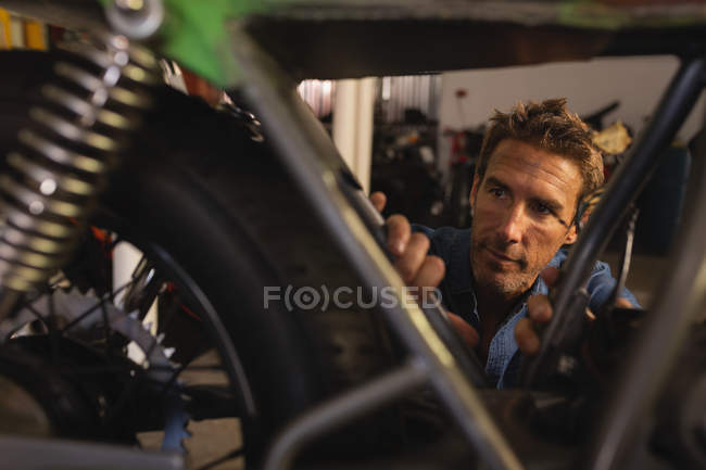 Vista frontal de la bicicleta masculina caucásica mecánica reparación de bicicletas en el garaje en el taller - foto de stock