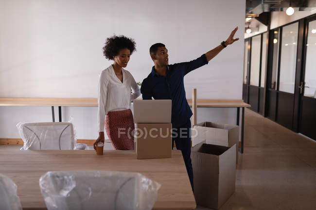 Вид сбоку на молодых бизнесменов смешанной расы, обсуждающих друг с другом в современном офисе — стоковое фото