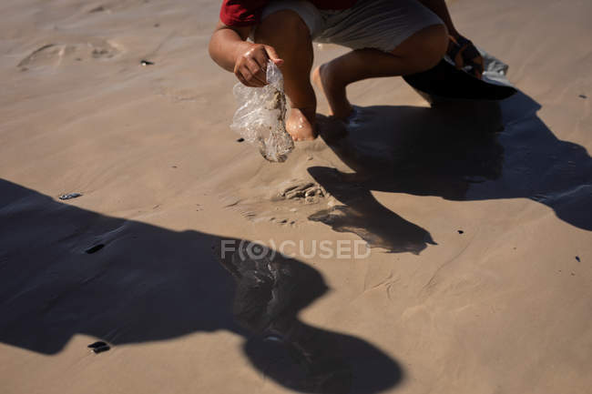 Low section of volunteer cleaning beach on a sunny day — Stock Photo