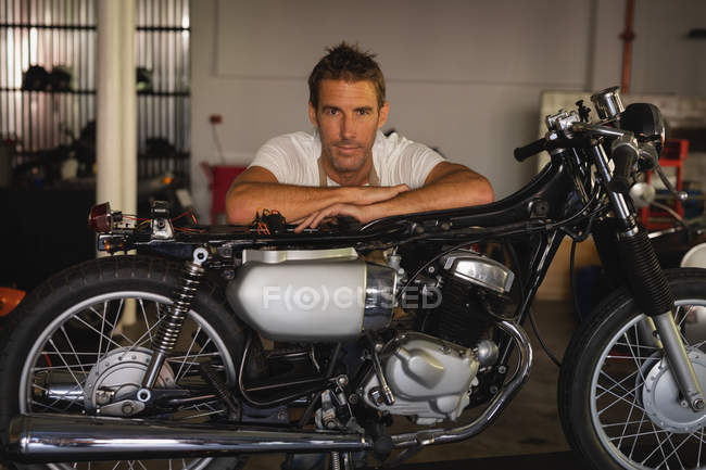 Portrait of Caucasian bike mechanic sitting with bike in garage — Stock Photo