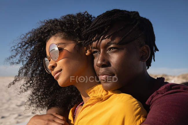 Vista frontal do casal romântico afro-americano em pé na praia em um dia ensolarado — Fotografia de Stock