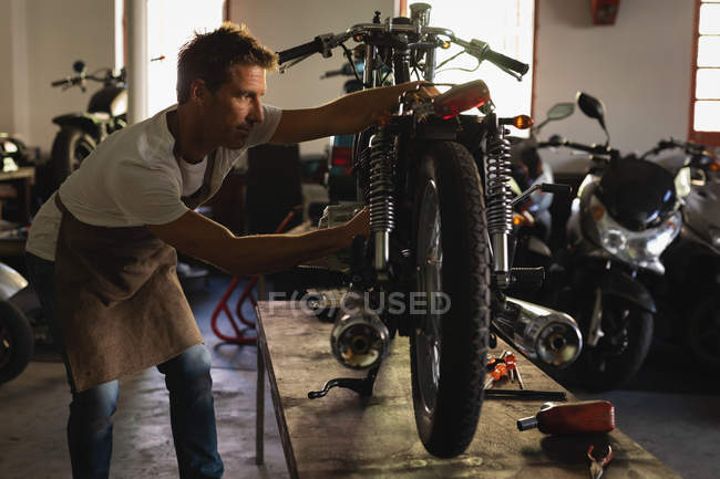 Side view of focused Caucasian bike Mechanic repairing bike in garage — Stock Photo