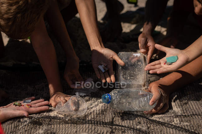Seção intermediária do grupo de voluntários encontrando resíduos com uma rede na praia em um dia ensolarado — Fotografia de Stock