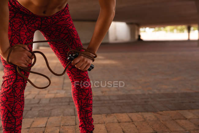 Mid section of woman resting after exercising under a bridge in the city — Stock Photo