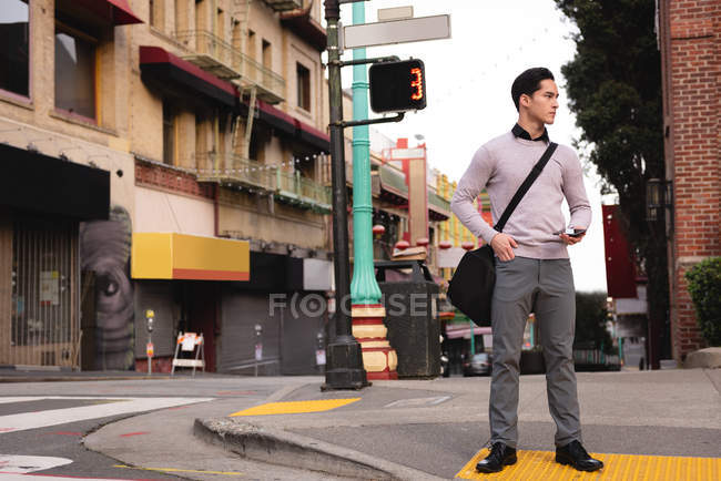 Вид на красивий азіатських чоловік, стоячи на розі міського тротуару очікування перетнути вулицю — стокове фото