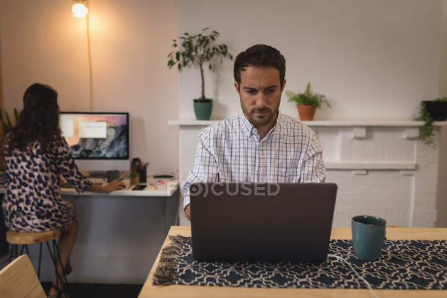 Vista frontal del ejecutivo masculino caucásico que trabaja en el ordenador portátil en el escritorio en la oficina - foto de stock