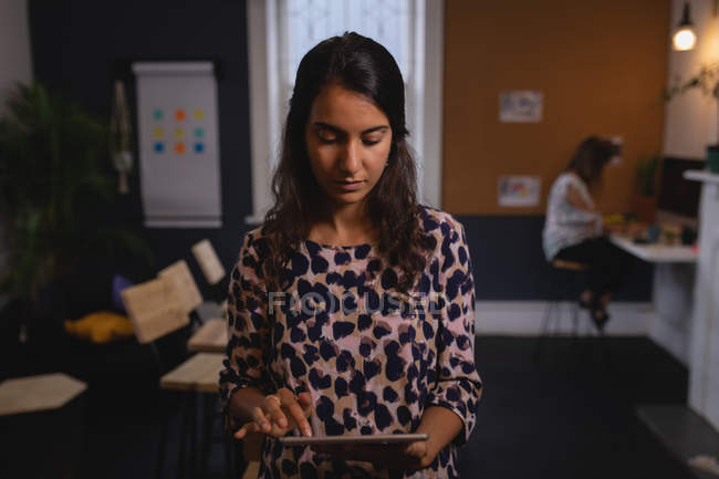 Обзор молодых красивых женщин-руководителей смешанной расы, работающих над цифровым планшетом в офисе — стоковое фото