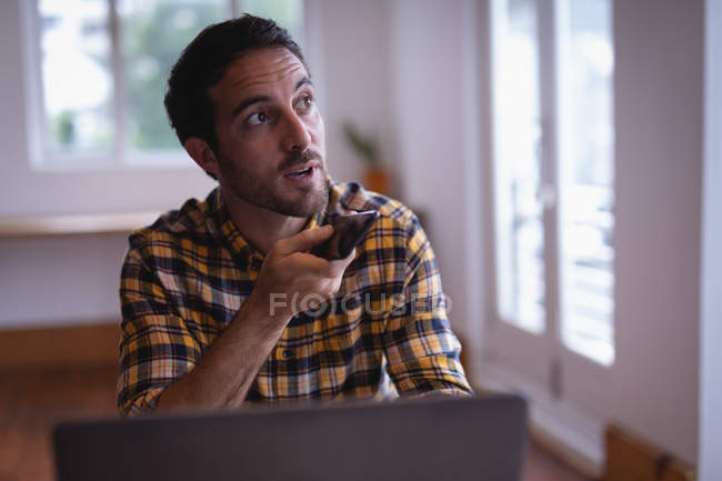 Front view of a smart Caucasian male executive talking on mobile phone while looking on his left in the office — Stock Photo