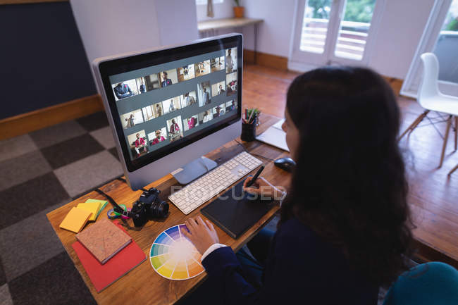 Sobre vista ombro de cabelo castanho mulher branca designer gráfico usando um tablet gráfico e computador em sua mesa no escritório — Fotografia de Stock