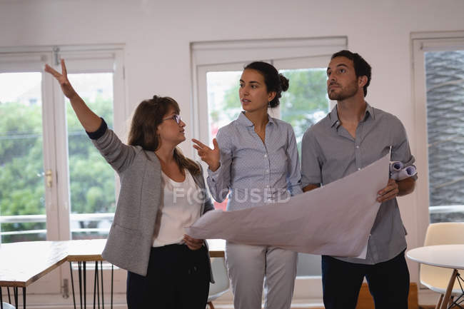 Front view of attentive Diverse business people discussing over blueprint in the office — Stock Photo