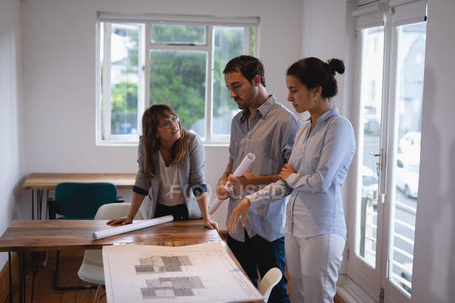 Side view of attentive Diverse business people discussing over blueprint in the office — Stock Photo