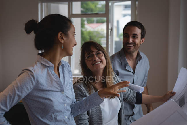 Боковой вид улыбающихся бизнесменов, обсуждающих синий цвет в офисе — стоковое фото