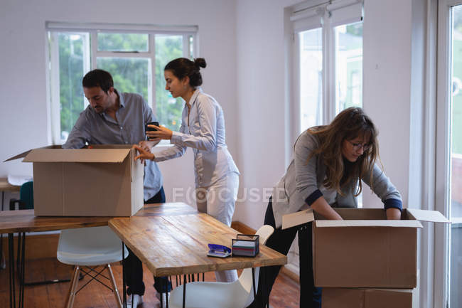 Вид сбоку на разнообразных бизнесменов, упаковывающих картонные коробки в офисе — стоковое фото