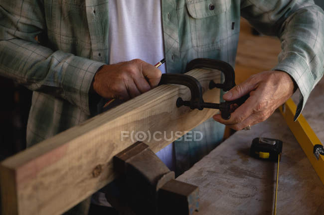 Mittelteil des Tischlers mit Schelle auf Holzplanke in Werkstatt — Stockfoto