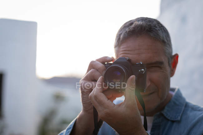 Vista frontal de hombre caucásico maduro haciendo clic en la foto con cámara digital - foto de stock