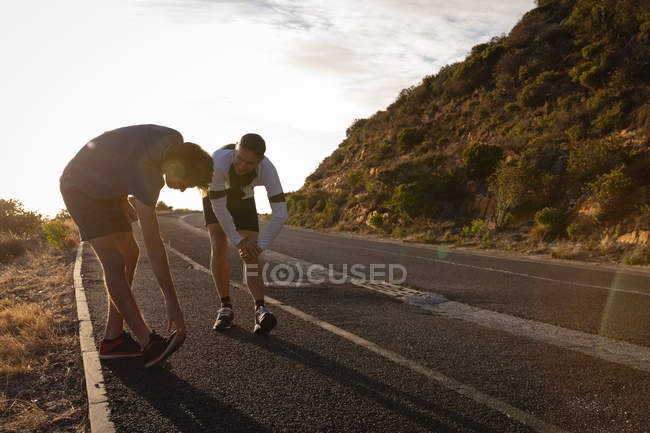 Вид сбоку на отца и сына кавказца, делающего упражнения на растяжку на дороге утром — стоковое фото