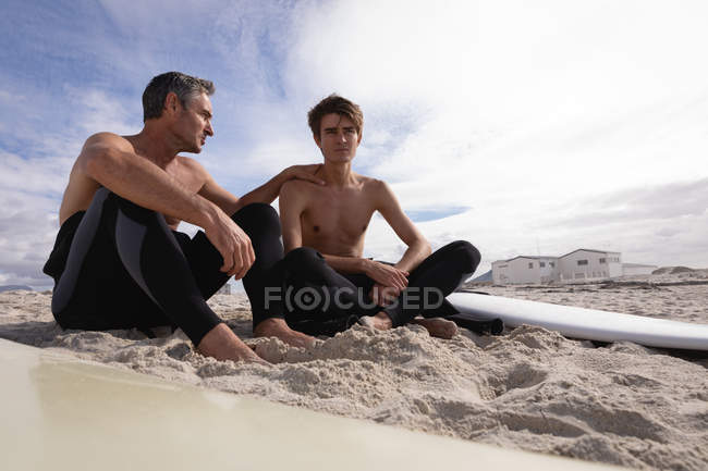Задний вид Кавказского отца и сына с доской для сёрфинга взаимодействуют друг с другом — стоковое фото