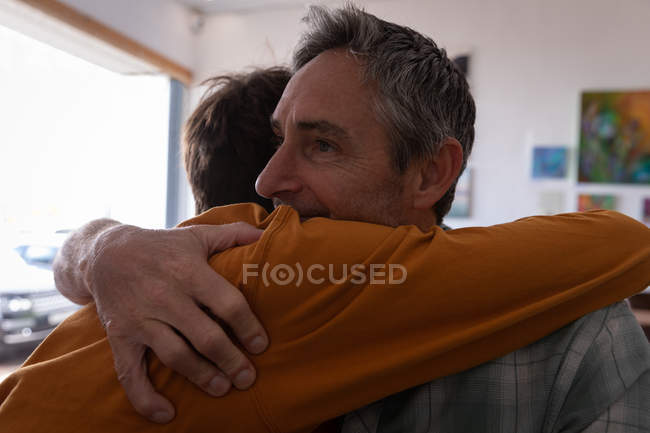 Primer plano de padre e hijo caucásicos abrazándose en casa - foto de stock