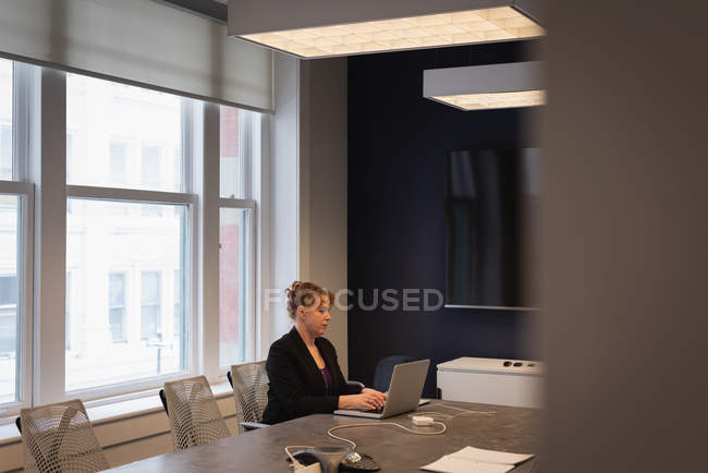 Вид збоку кавказької ділової жінки з використанням ноутбука в конференц-залі в офісі — стокове фото