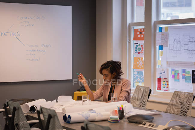 Front view of African American female architect reviewing blueprints in conference room at office — Stock Photo