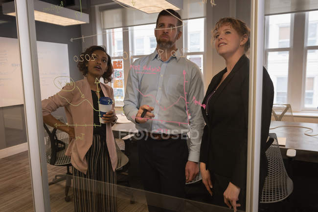 Vue de face de divers hommes d'affaires projetant sur un mur de verre dans la salle de conférence au bureau — Photo de stock