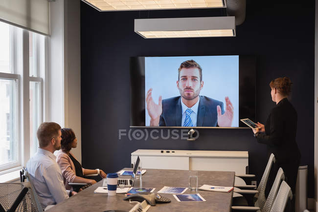 Visão traseira de diversos executivos de negócios fazendo videoconferência em reunião de negócios no escritório — Fotografia de Stock