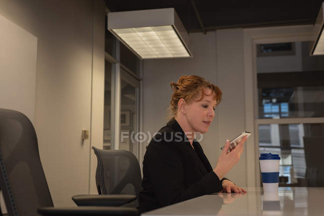 Vista lateral de la mujer de negocios caucásica hablando por teléfono móvil en la sala de conferencias en la oficina - foto de stock