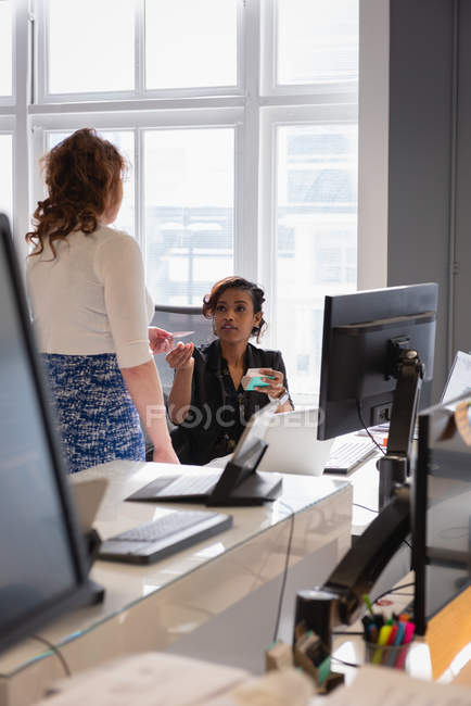 Вид збоку Кавказького жіночого бізнесу виконавчого даючи візитна картка її колега в офісі — стокове фото